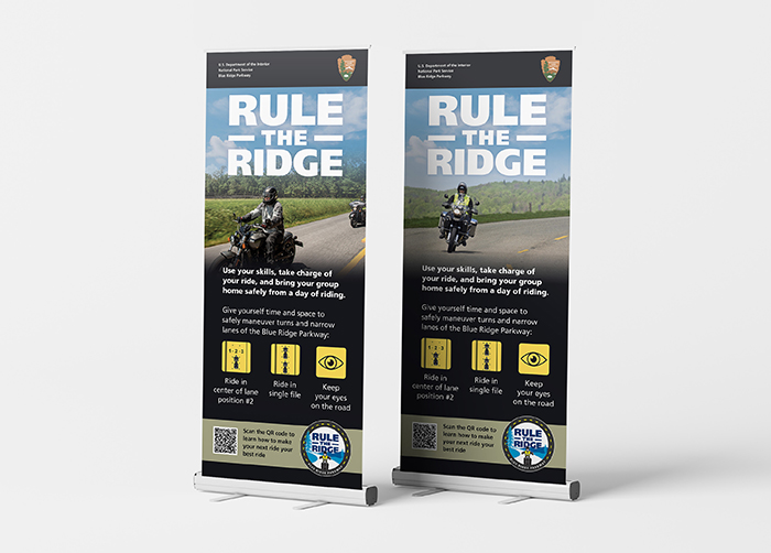 Pull-up banners with an image of people riding motorcycles on a mountain road with rifing safety reminders.
